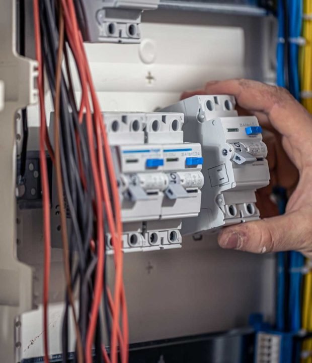a-male-electrician-works-in-a-switchboard-with-an-7J8VVT4.jpg